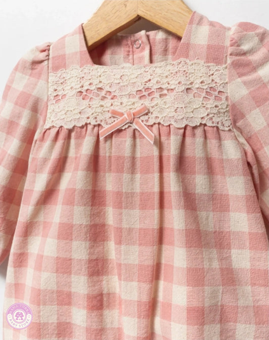 Close-up of pink checkered cotton jumpsuit for baby girls with delicate lace panel and bow detail