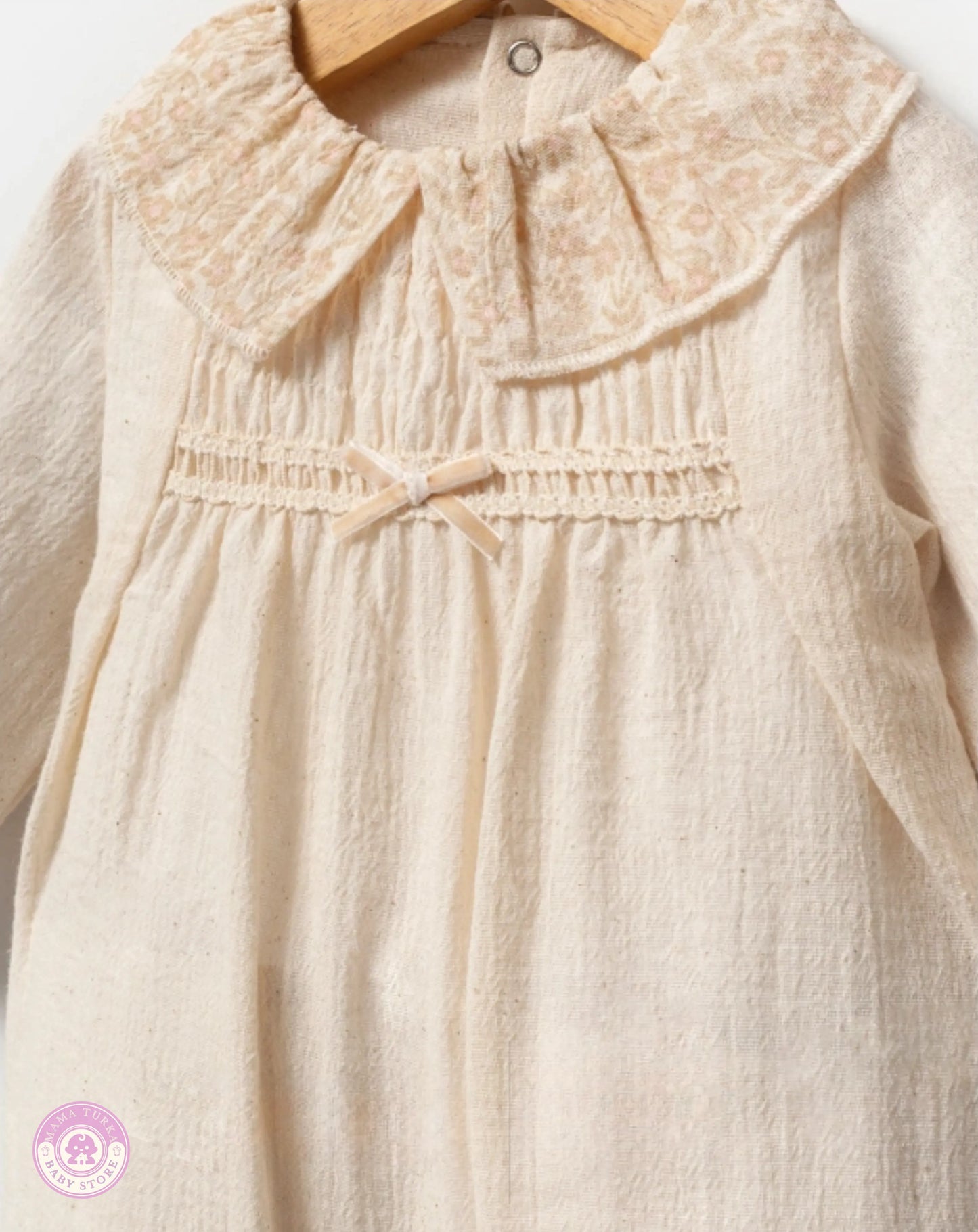Close-up of soft ivory baby girl cotton jumpsuit with delicate collar and refined finishing