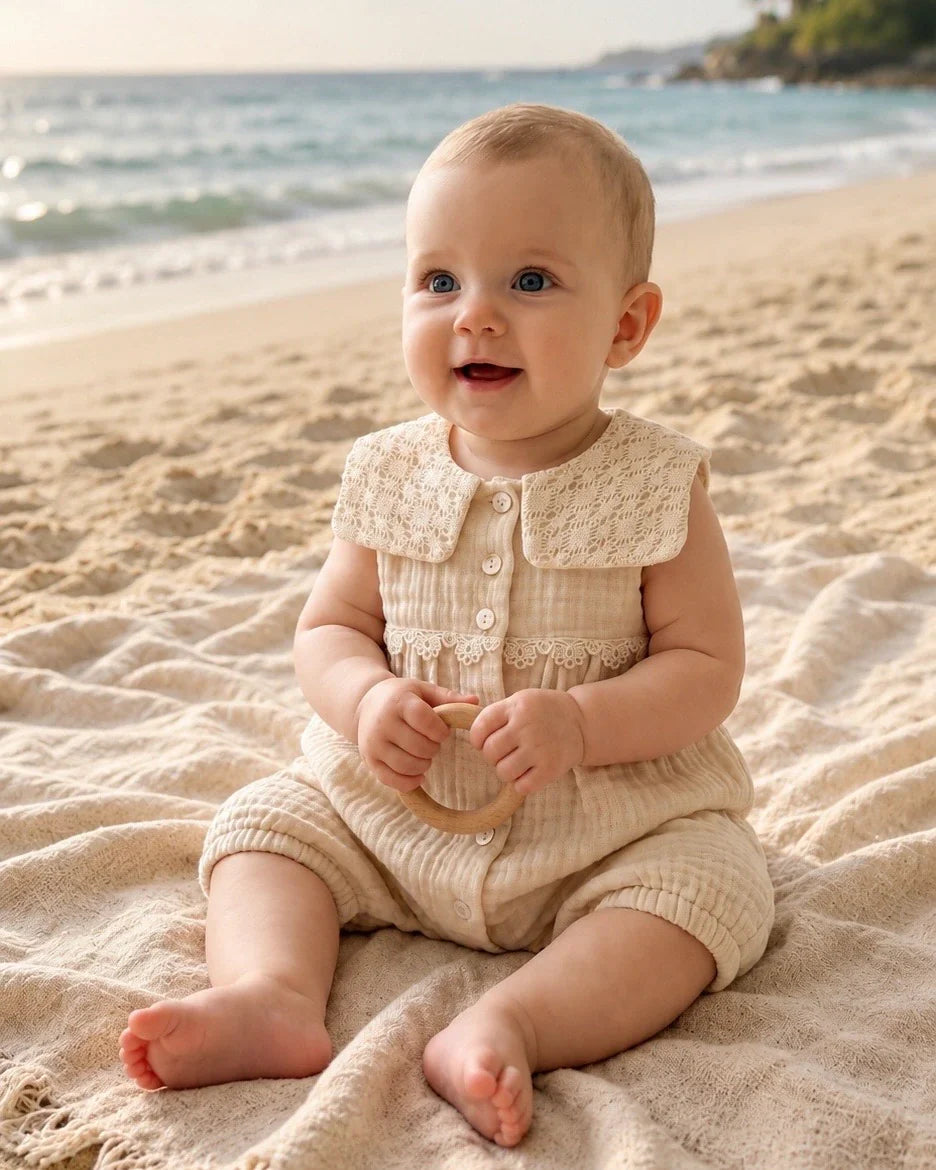 Baby girl romper in soft cotton muslin with lace collar, worn outdoors on a blanket