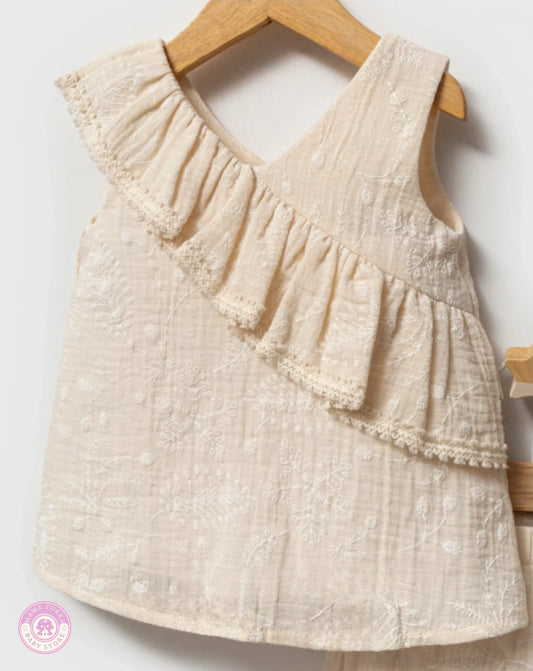 Close-up of beige cotton ruffle top with delicate embroidered floral details for baby girls