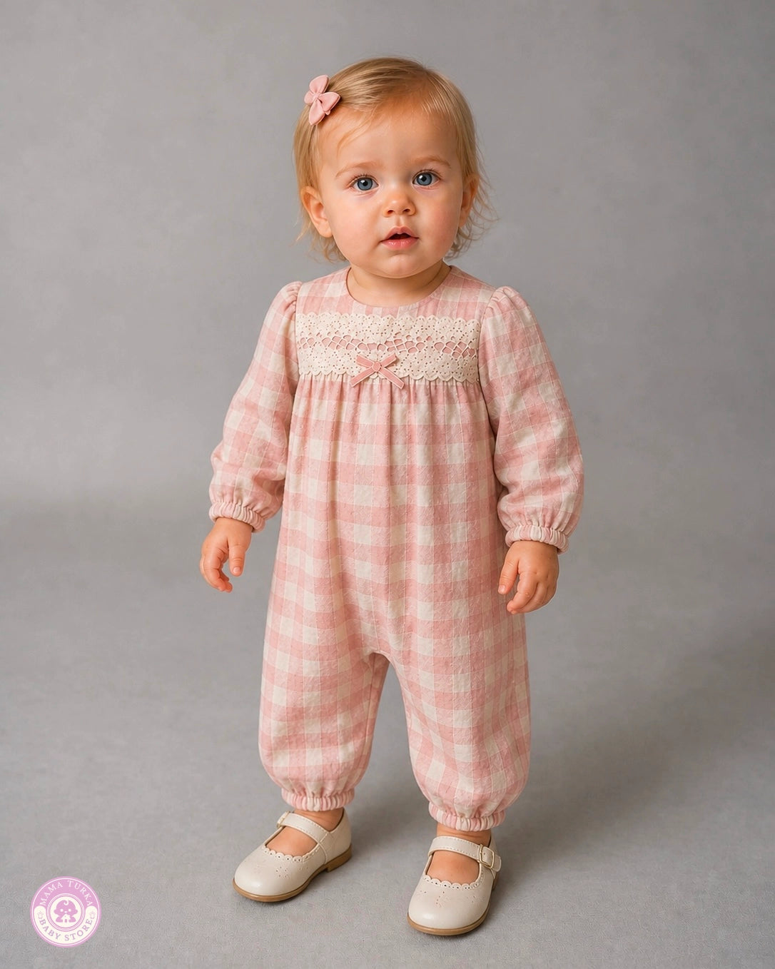 Baby girl wearing a pink checkered cotton jumpsuit with lace detail and soft bow accent