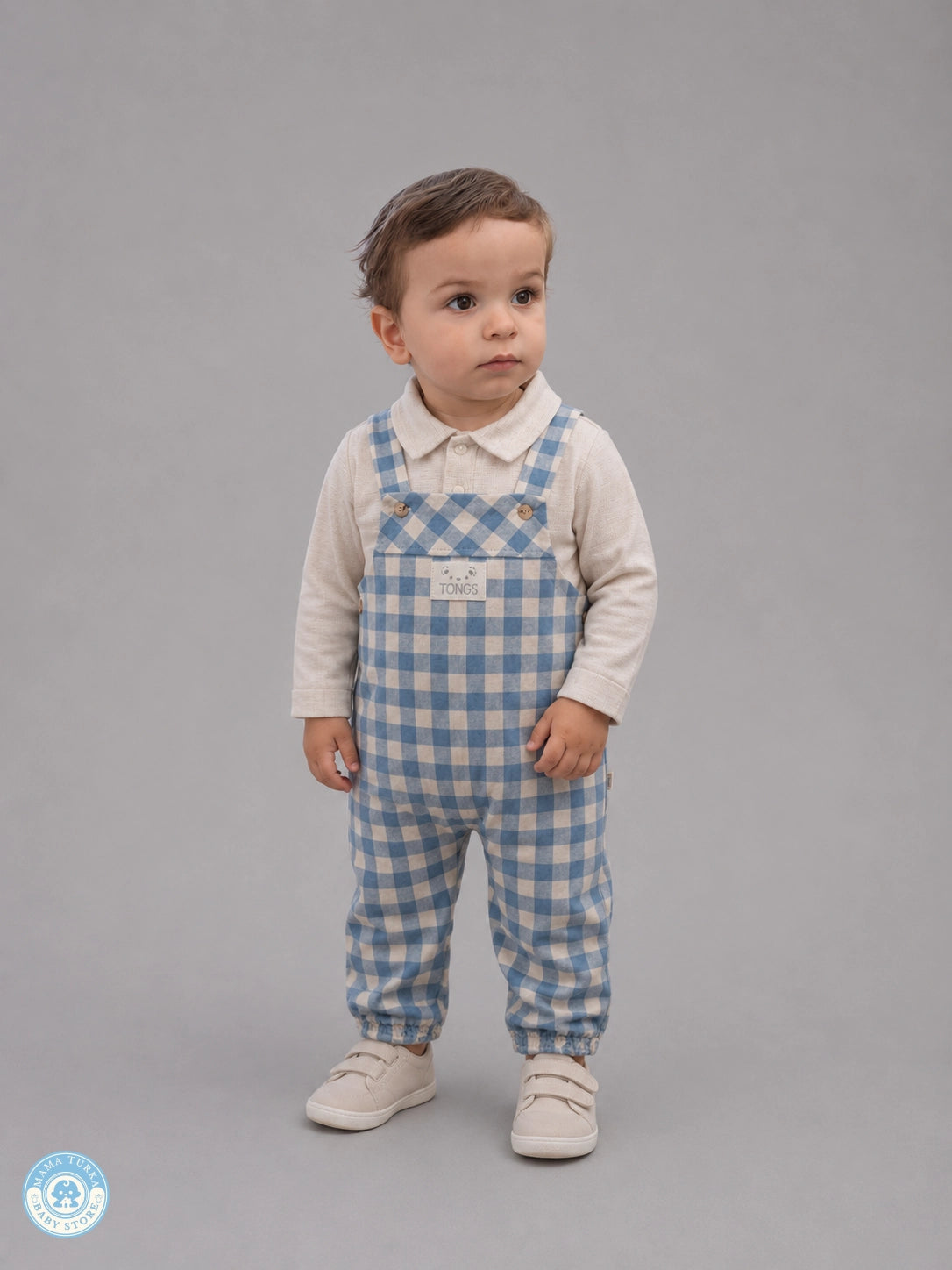 Baby boy wearing blue gingham overall set with cream shirt