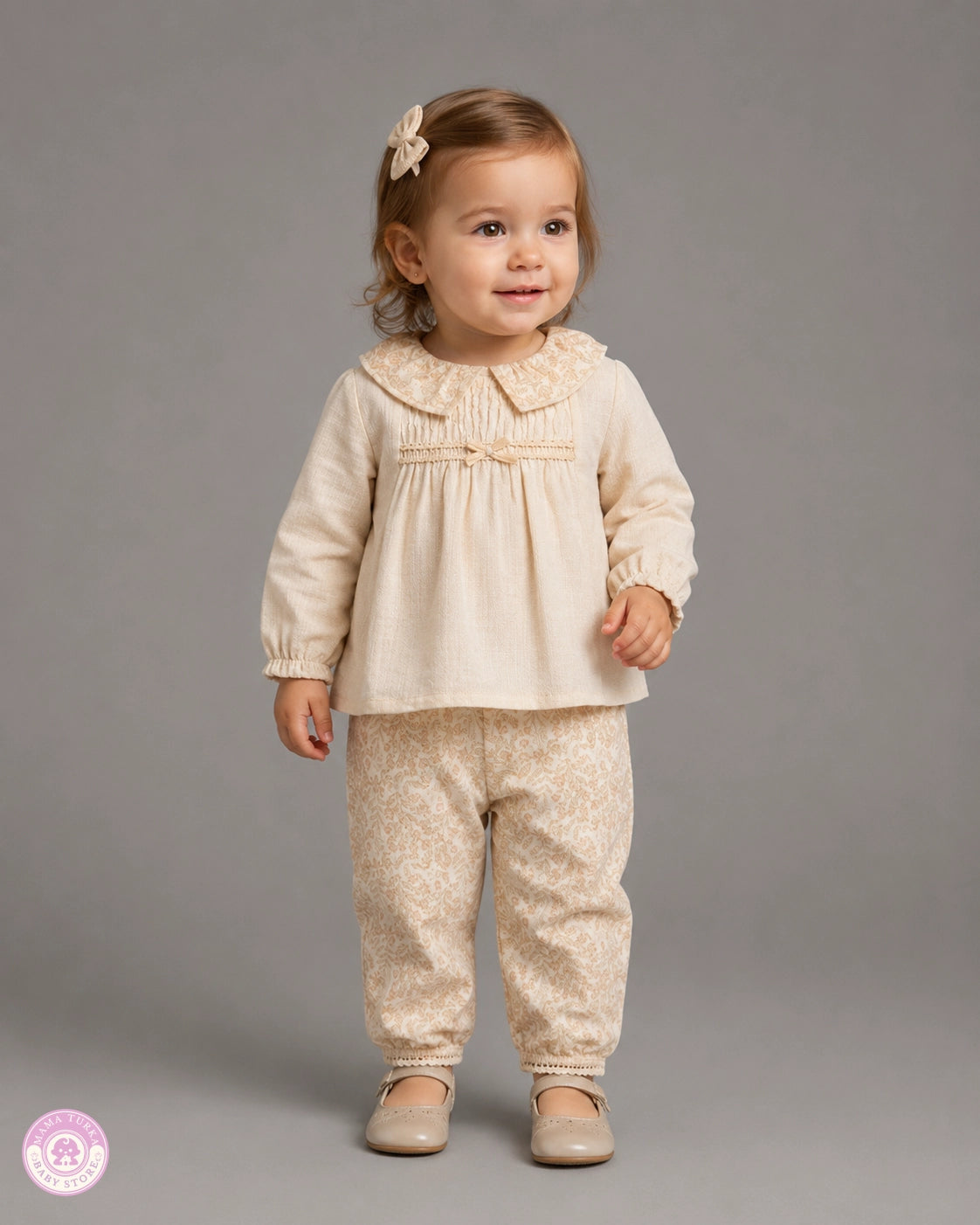 Baby girl wearing cream cotton blouse and floral trousers outfit set