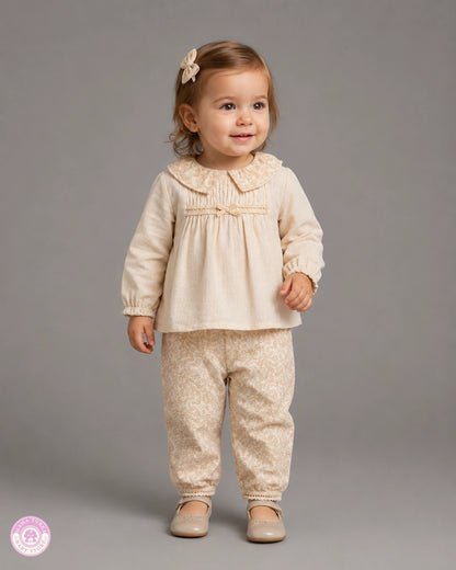Baby girl wearing cream cotton blouse and floral trousers outfit set