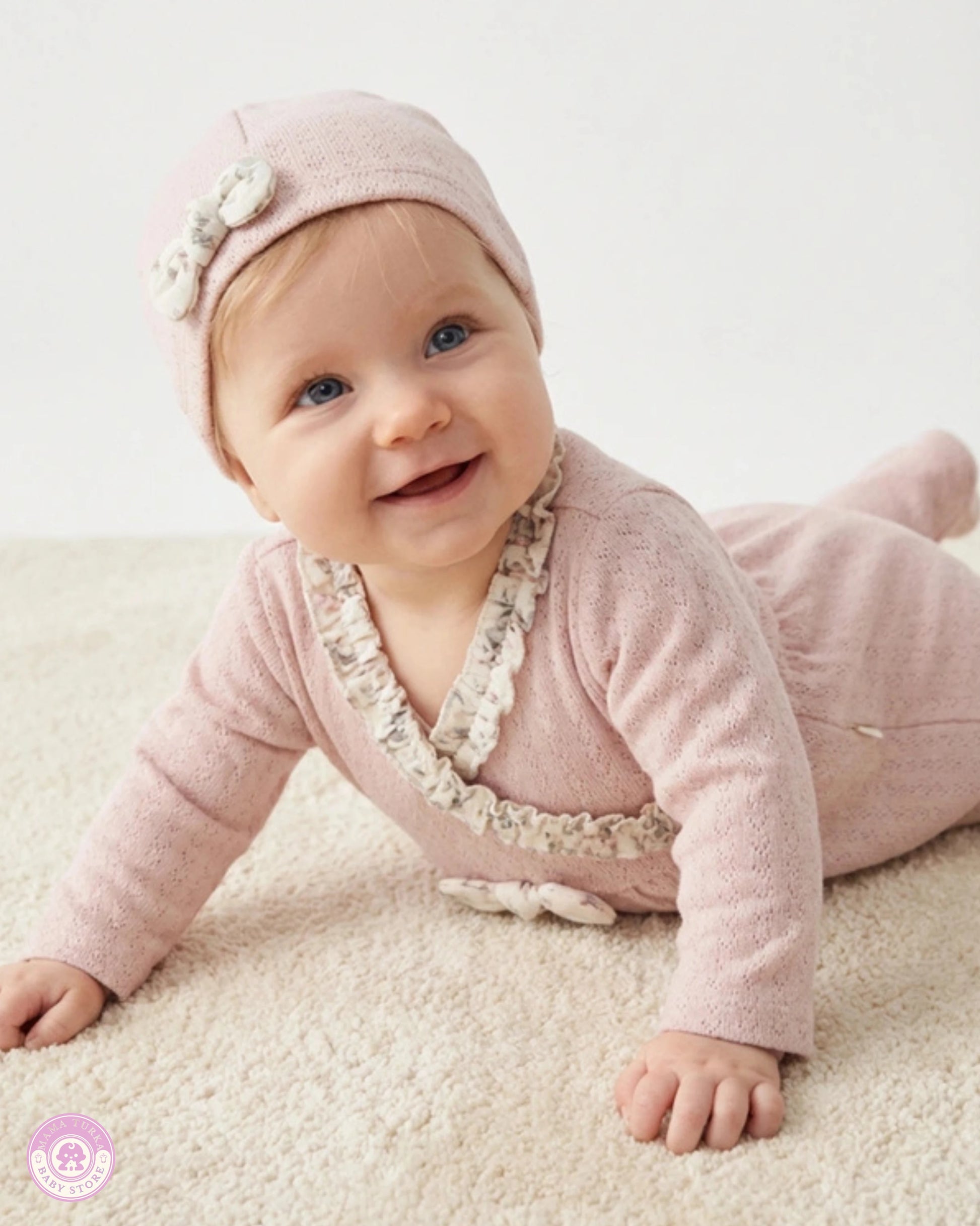 Baby wearing pink newborn set with matching hat and delicate ruffle details