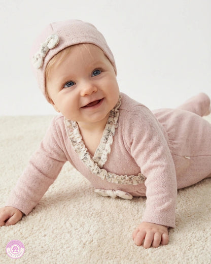 Baby wearing pink newborn set with matching hat and delicate ruffle details