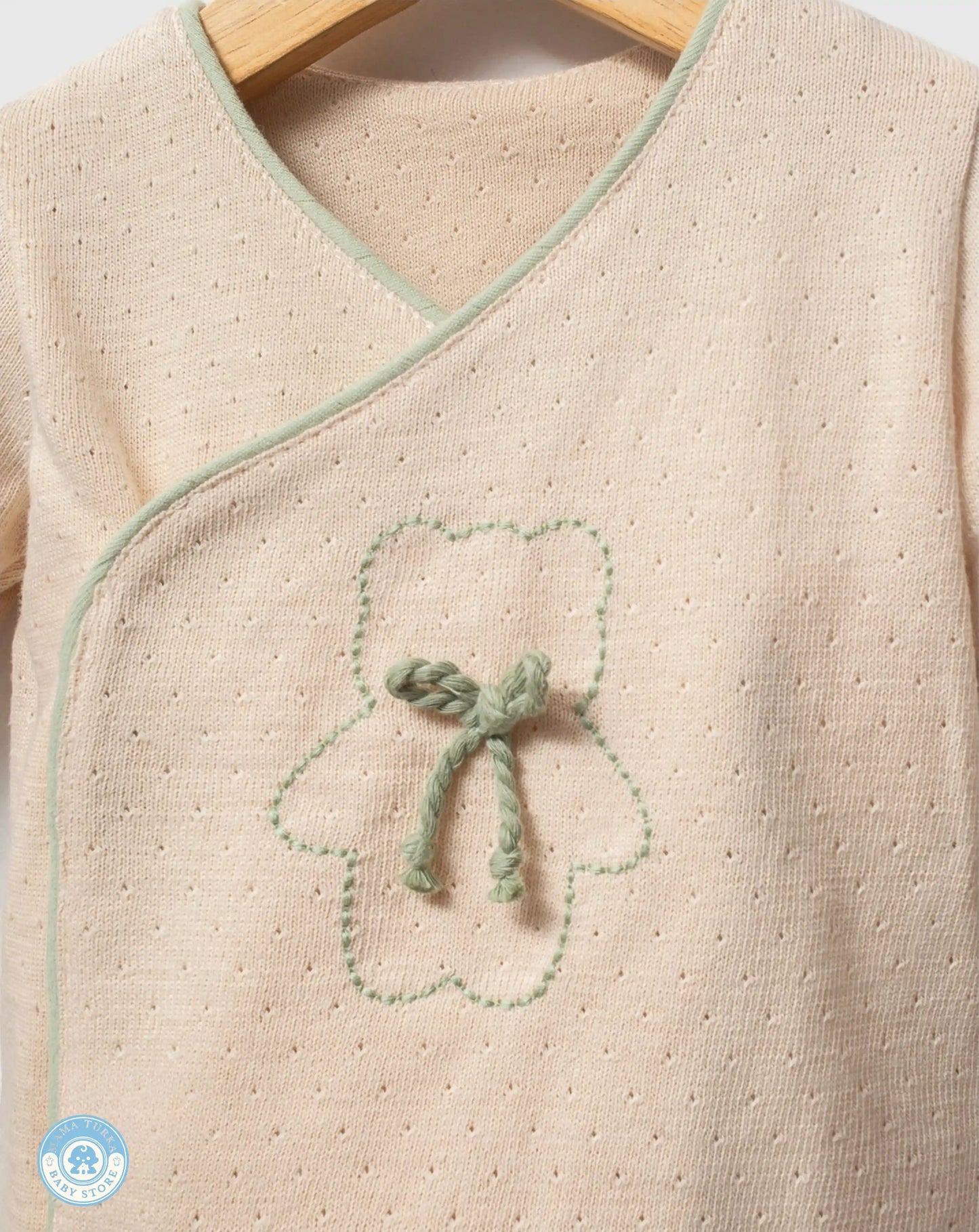 Close-up of sage green newborn baby cotton wrap top with delicate embroidery