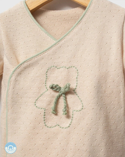 Close-up of sage green newborn baby cotton wrap top with delicate embroidery
