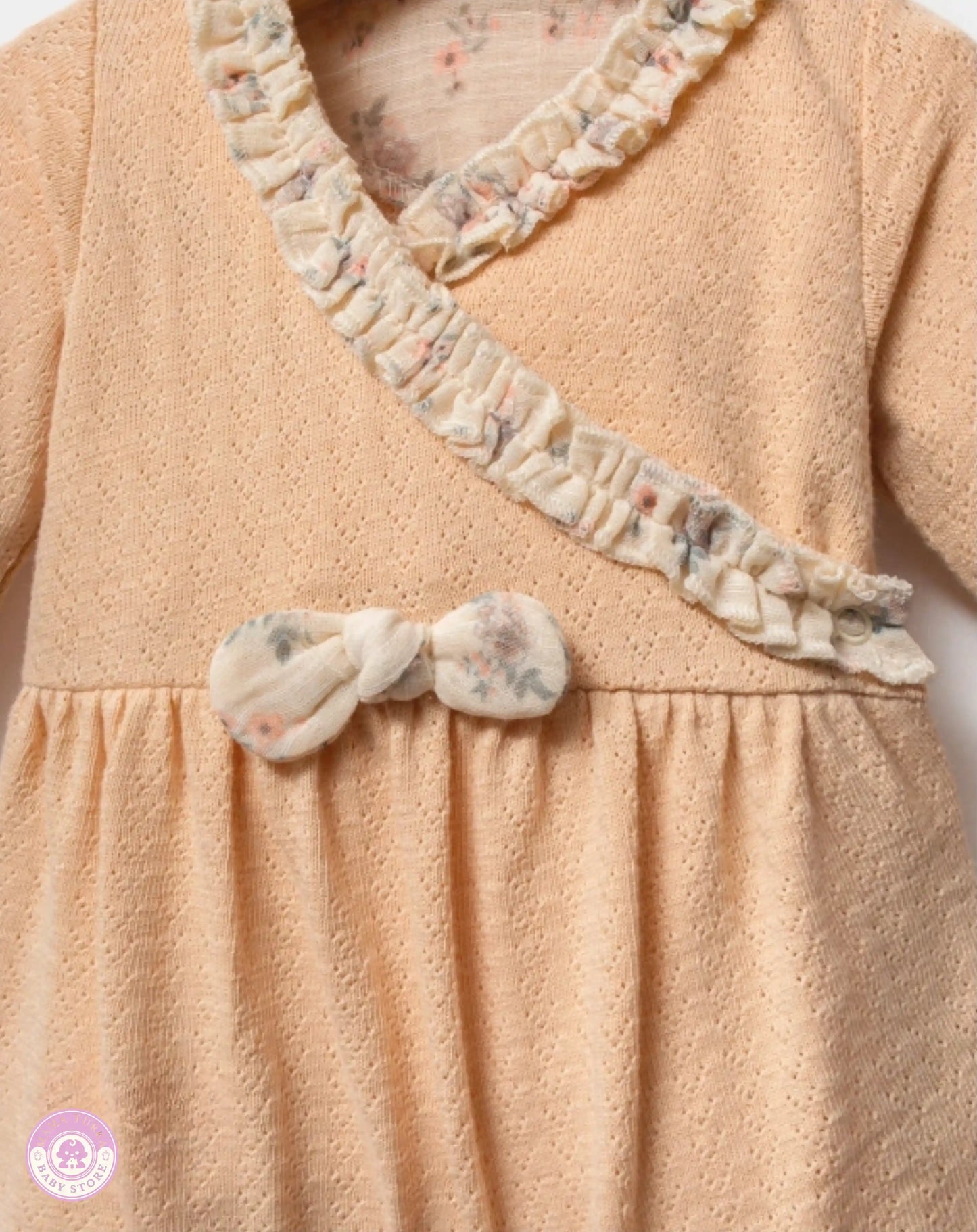 Close-up of yellow newborn girl set with ruffle and bow details